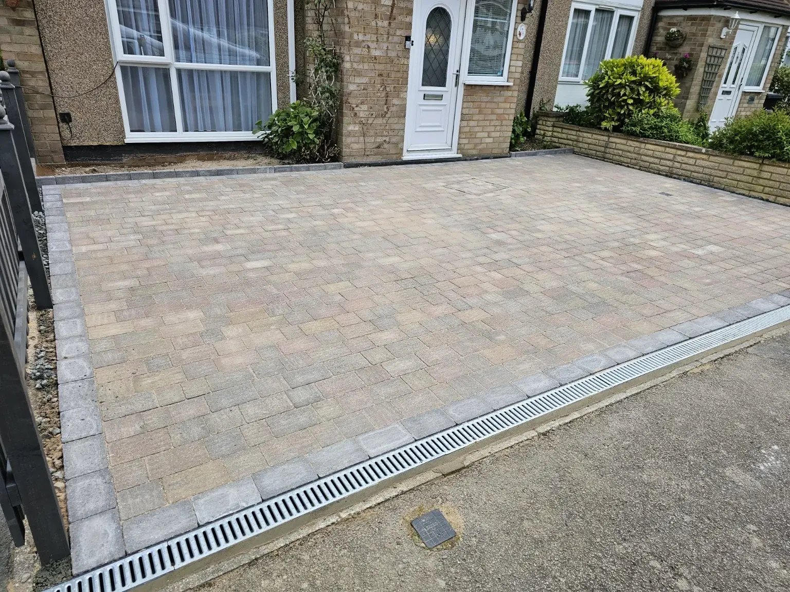 Finished block paved driveway with a drainage channel outside a brick house